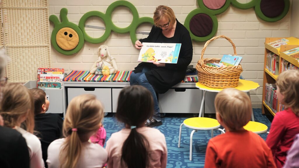 Kirjastovirkailija lukee kirjaa lapsille